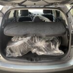 Kofferraum eines Autos mit verpacktem Ersatzreifen, geöffnet, gezeigt auf einem Parkplatz.