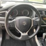 Lenkrad eines Suzuki-Autos mit Tempomatbedienung, Tachometer und Mittelkonsole im Cockpit.