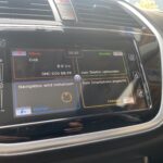 Auto-Infotainmentsystem zeigt Radio, Navigation und Telefonstatus auf Bildschirm an. Navigation wird initialisiert.