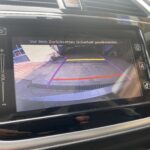 Auto-Rückfahrkamera zeigt farbige Linien zur Orientierung auf Display; Warnhinweis zur Sicherheit beim Zurücksetzen.