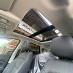 Auto-Innenraum mit schwarzem Sitz und Panoramadachansicht, JESA Automobile Schild im Freien sichtbar.