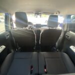 Innenraum eines Autos von hinten, mit Blick auf Vordersitze und Armaturenbrett bei Sonnenlicht.