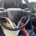 Lenkrad eines Suzuki-Autos, Armaturenbrett mit Bedienungselementen und Display, sportlicher Innenraum.