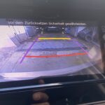 Rückfahrkamera-Display im Auto zeigt farbige Leitlinien zum sicheren Einparken in einer Garage.